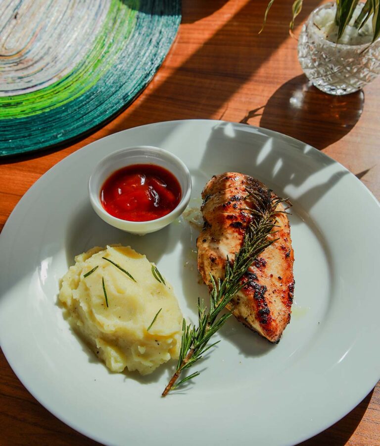 Mashed potatoes and seared chicken topped with herbs 
